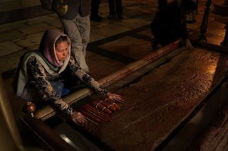 A pilgrim runs her hand across the Stone of Anointing in the Church of the Holy Sepulchre in 2014. This stone is traditionally held to be the spot where Jesus Christ's body was prepared for burial after crucifixion. Pilgrims have been coming to the church