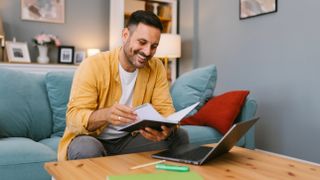 A man sitting on a sofa by a coffee table using a PC that&#039;s on the table