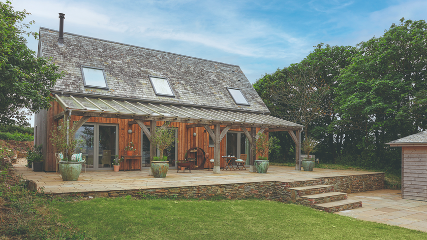 Exterior of the house which backs onto a garden and patio with plant pots and veranda 