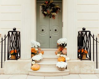 front porch in autumn with white flowers and pumpkins