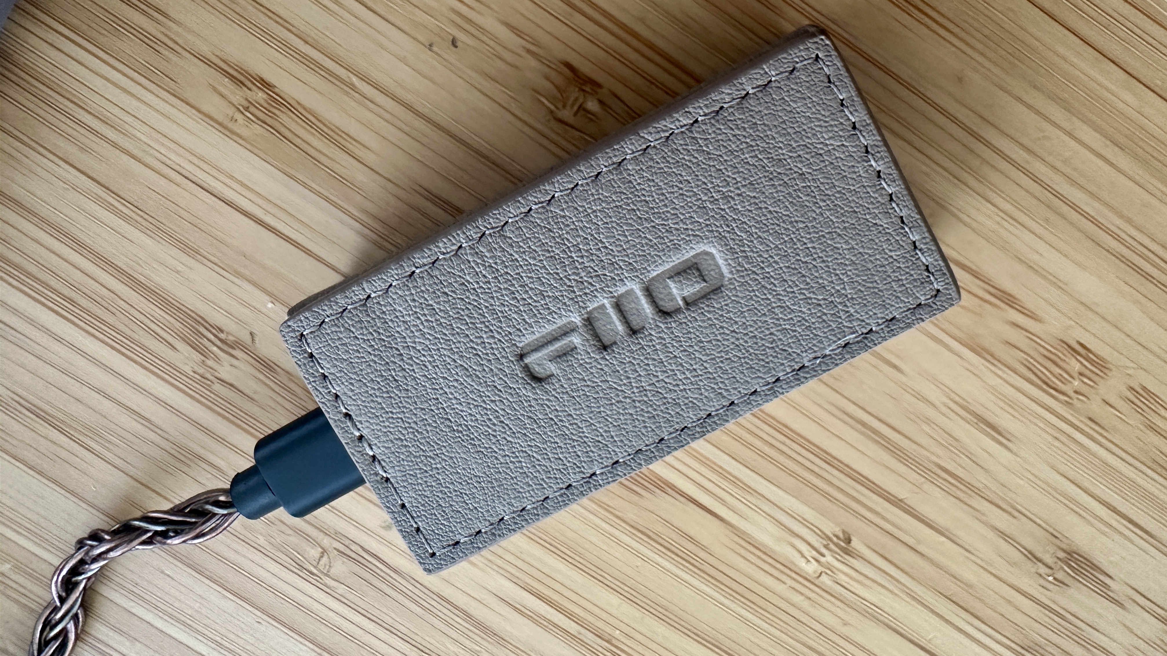 Magnetic case of the FiiO QX13 headphone amp/DAC on a wooden surface