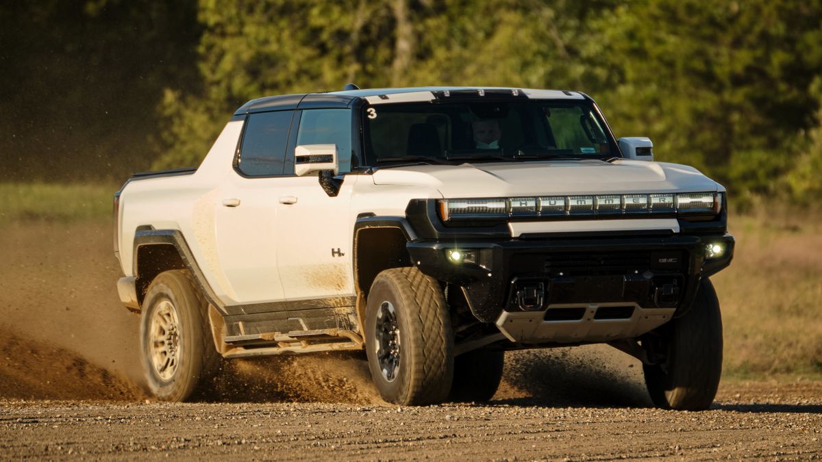 A white Hummer EV driving on sand