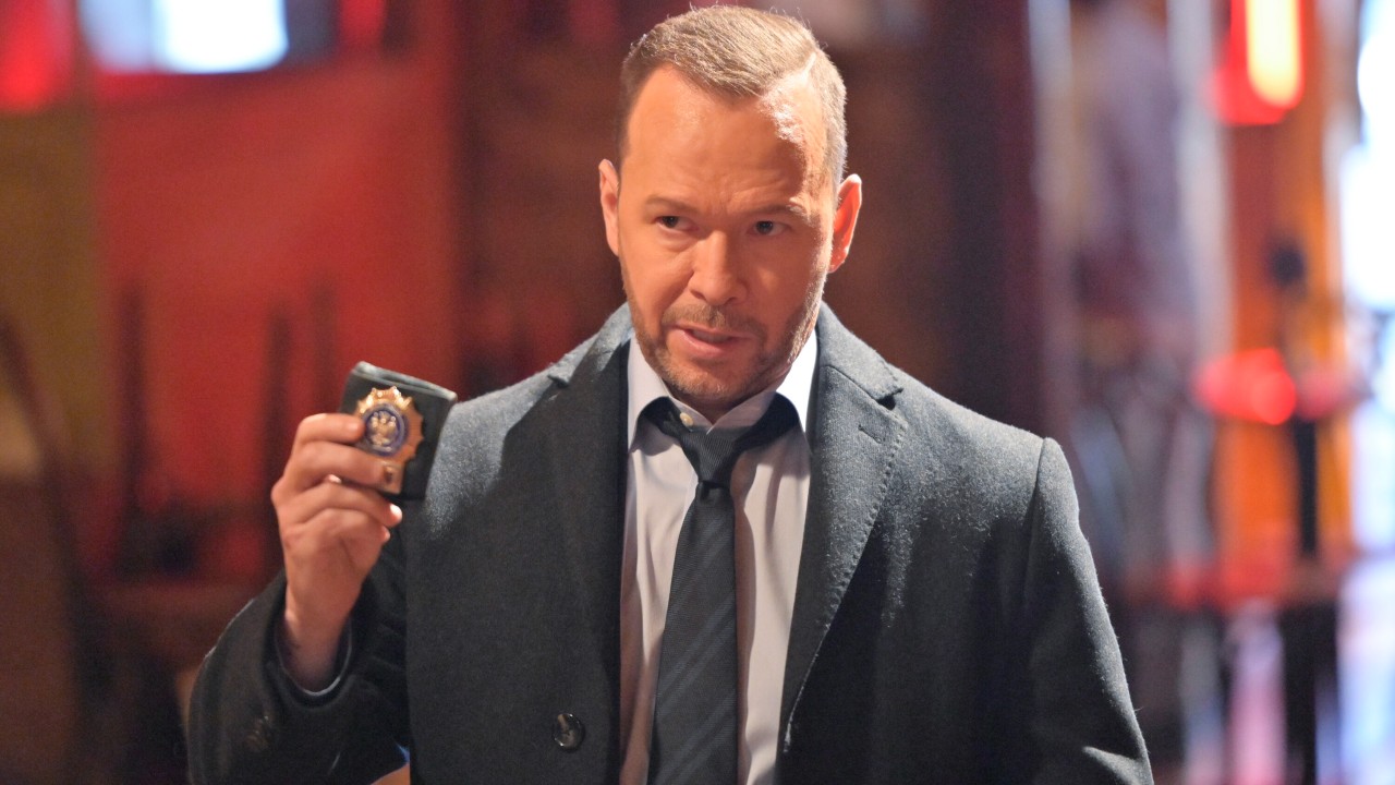 Donnie Wahlberg holding up a badge in his left hand in Blue Bloods. 