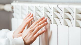 Woman warming hands on radiator