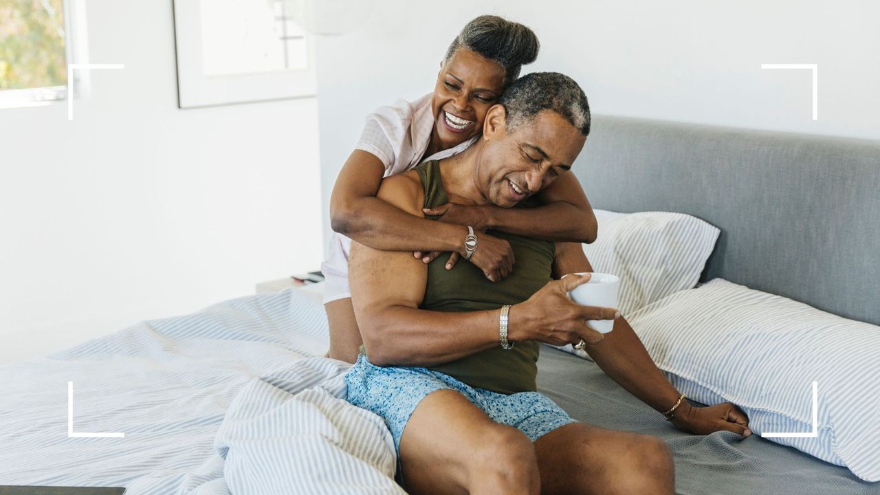 Couple in bed together laughing and smiling, representing the bow and arrow sex position