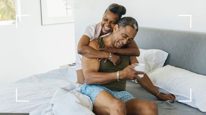 Couple in bed together laughing and smiling, representing the bow and arrow sex position