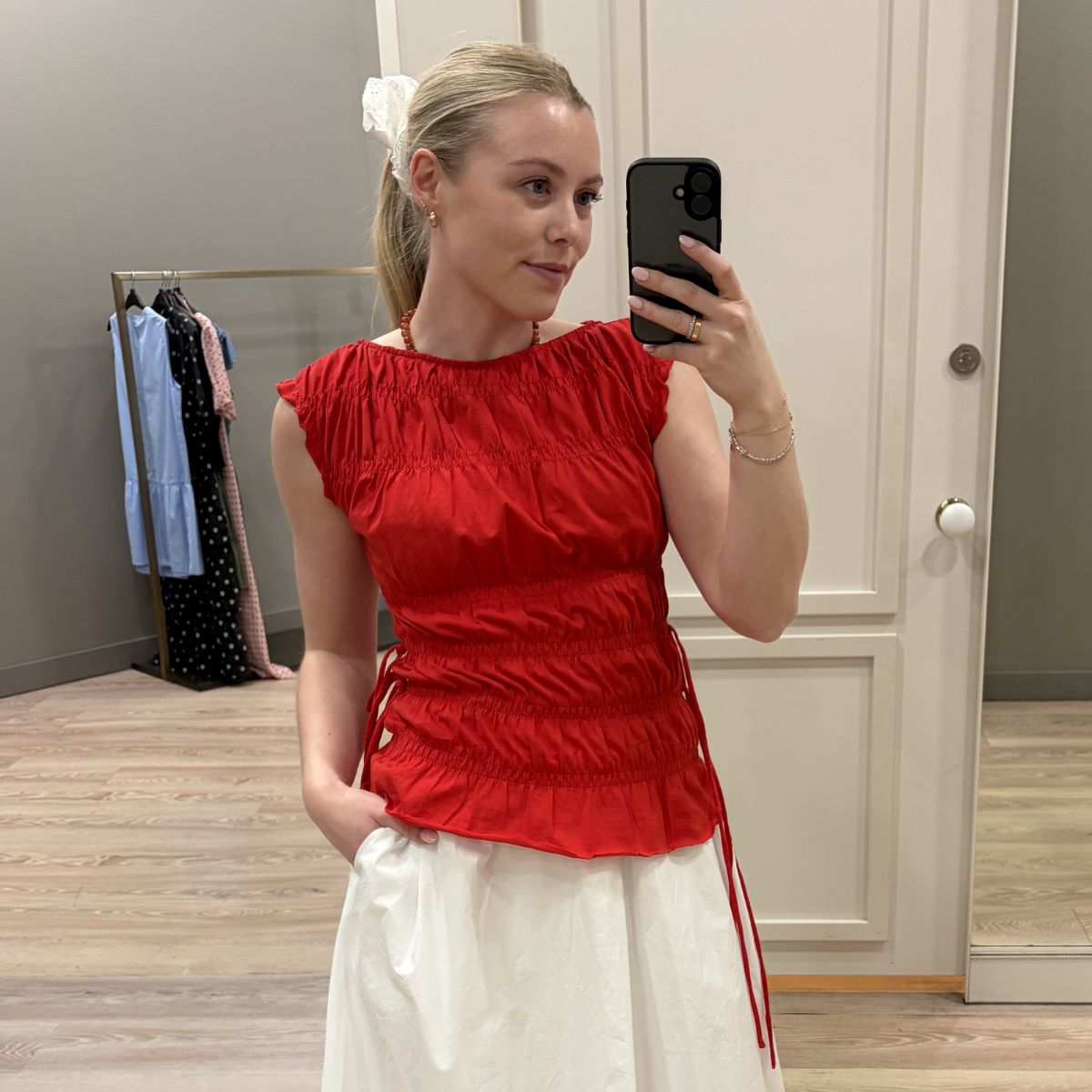 Woman wears red top, white skirt and white scrunchie
