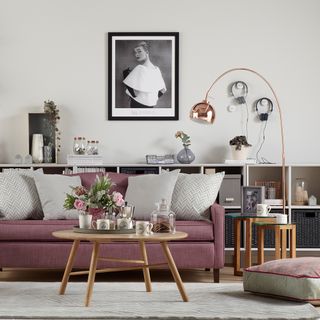 living area with white wall and picture frame and pink sofa and cushions and shelves