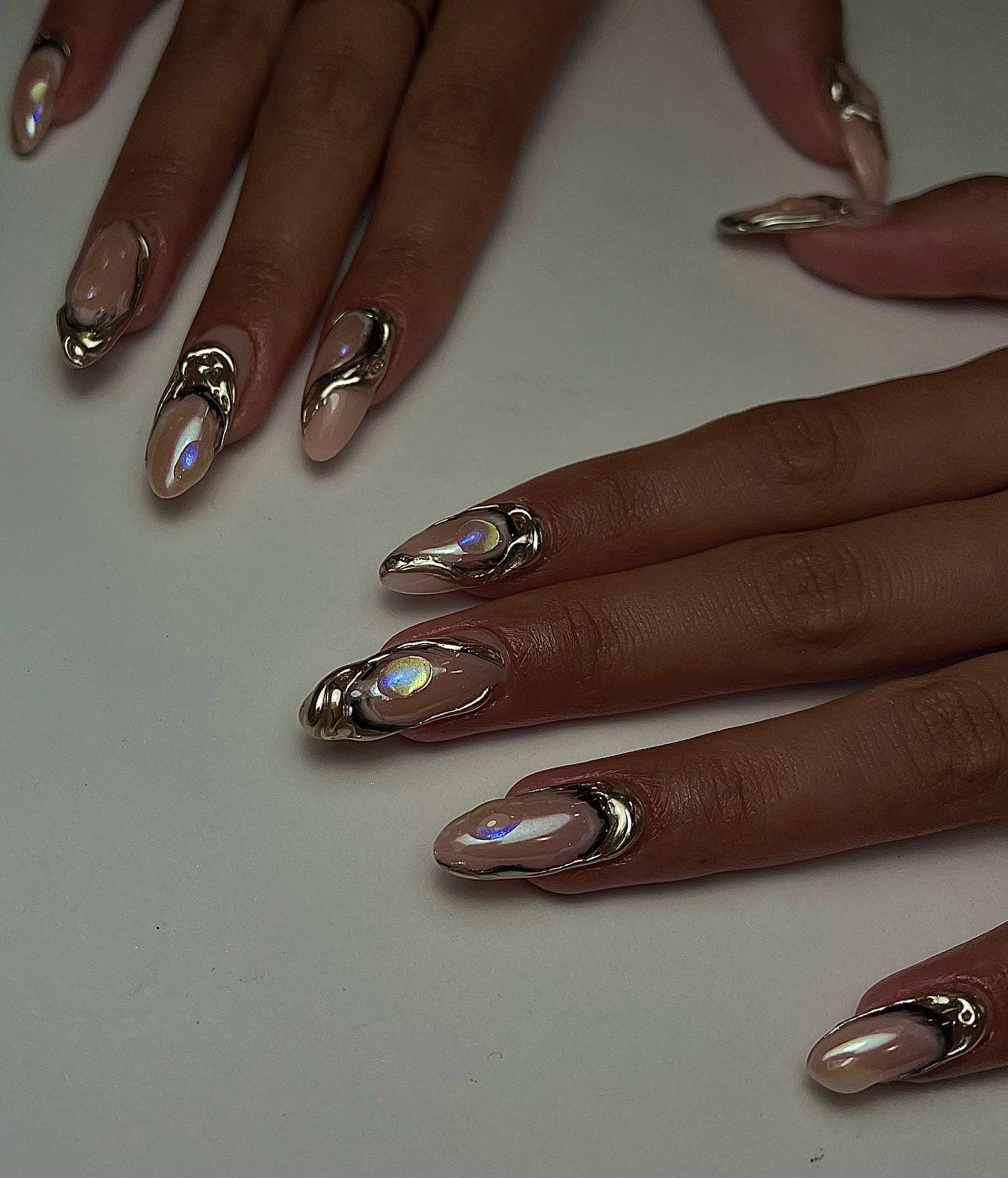 almond-shaped nude nails with raised chrome borders and iridescent opal accents that look like oysters