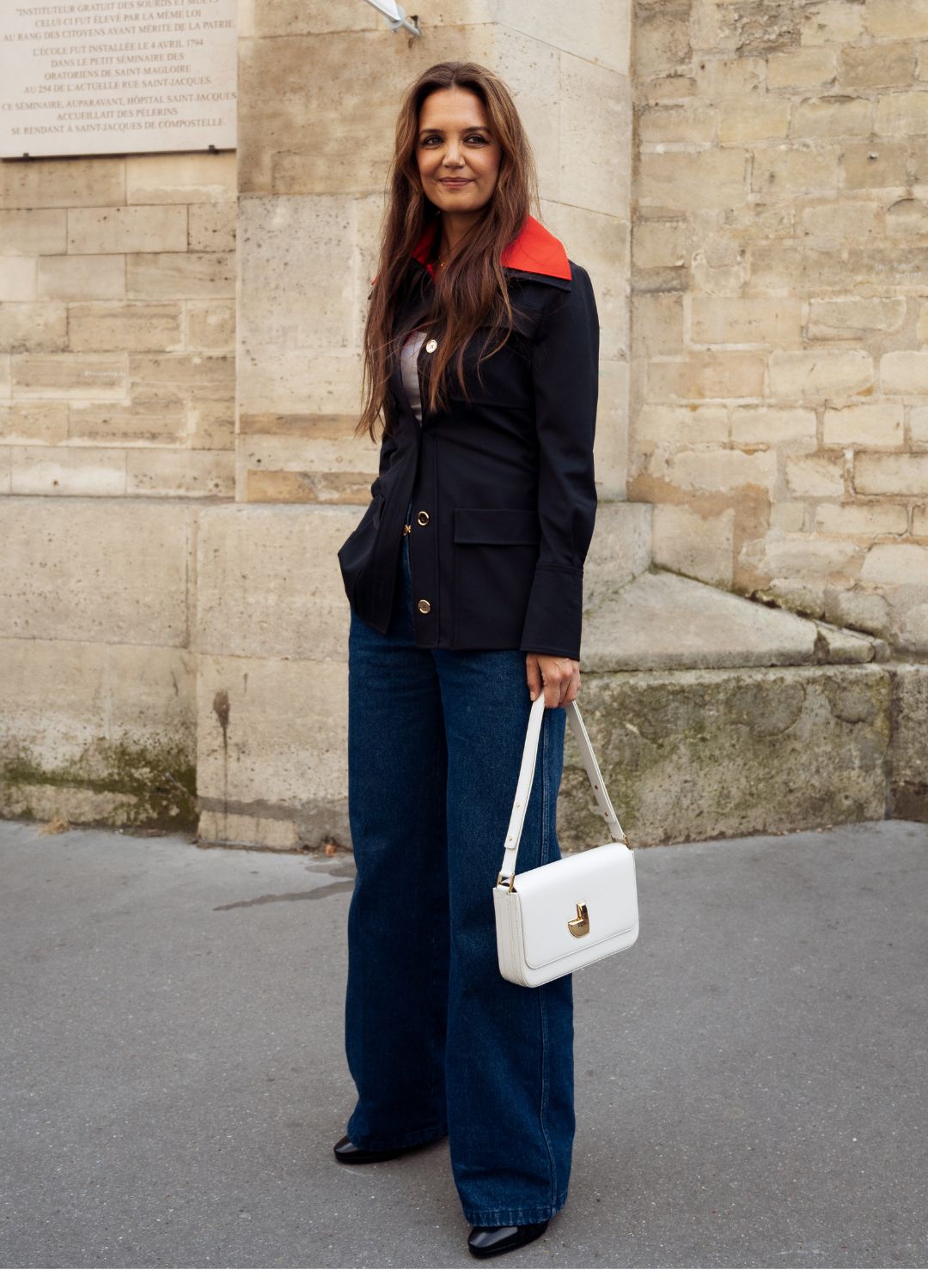 Katie Holmes wears a navy blue and red jacket, dark blue denim jeans, black shoes and a white bag outside Patou during the Haute Couture Fall/Winter 2024/2025 as part of Paris Fashion Week on June 27, 2024 in Paris, France.