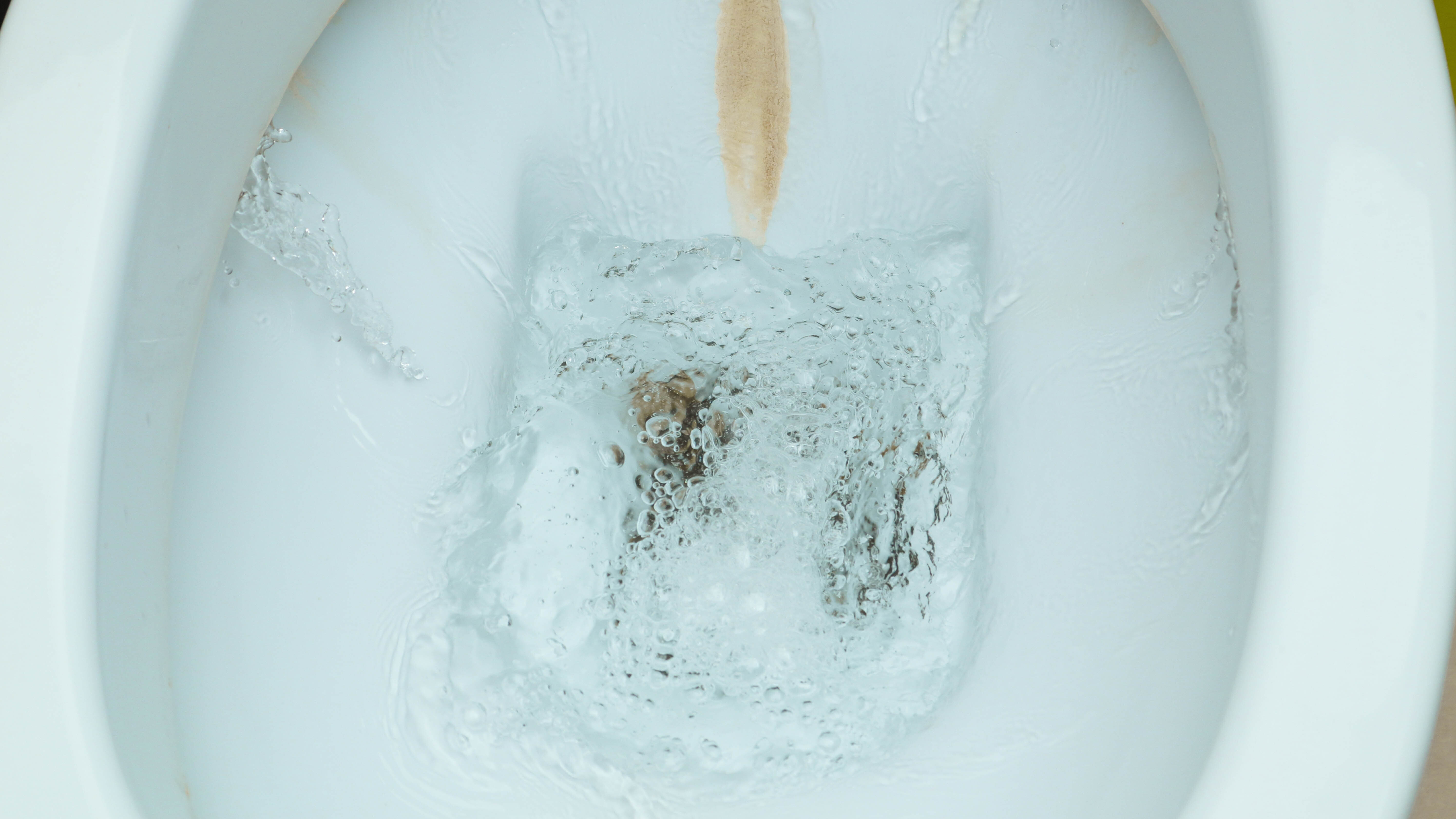 Toilet pan being flushed showing brwon staining from limescale