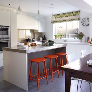 white cabinets and island with stainless steel island worktop and red stools