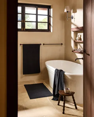 modern bathroom with freestanding bath and stool with towel over hanger, on the floor and over the side of the bath