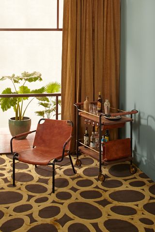 ... and an armchair and a bar cart, pictured here with rugs by Rockwell for The Rug Company