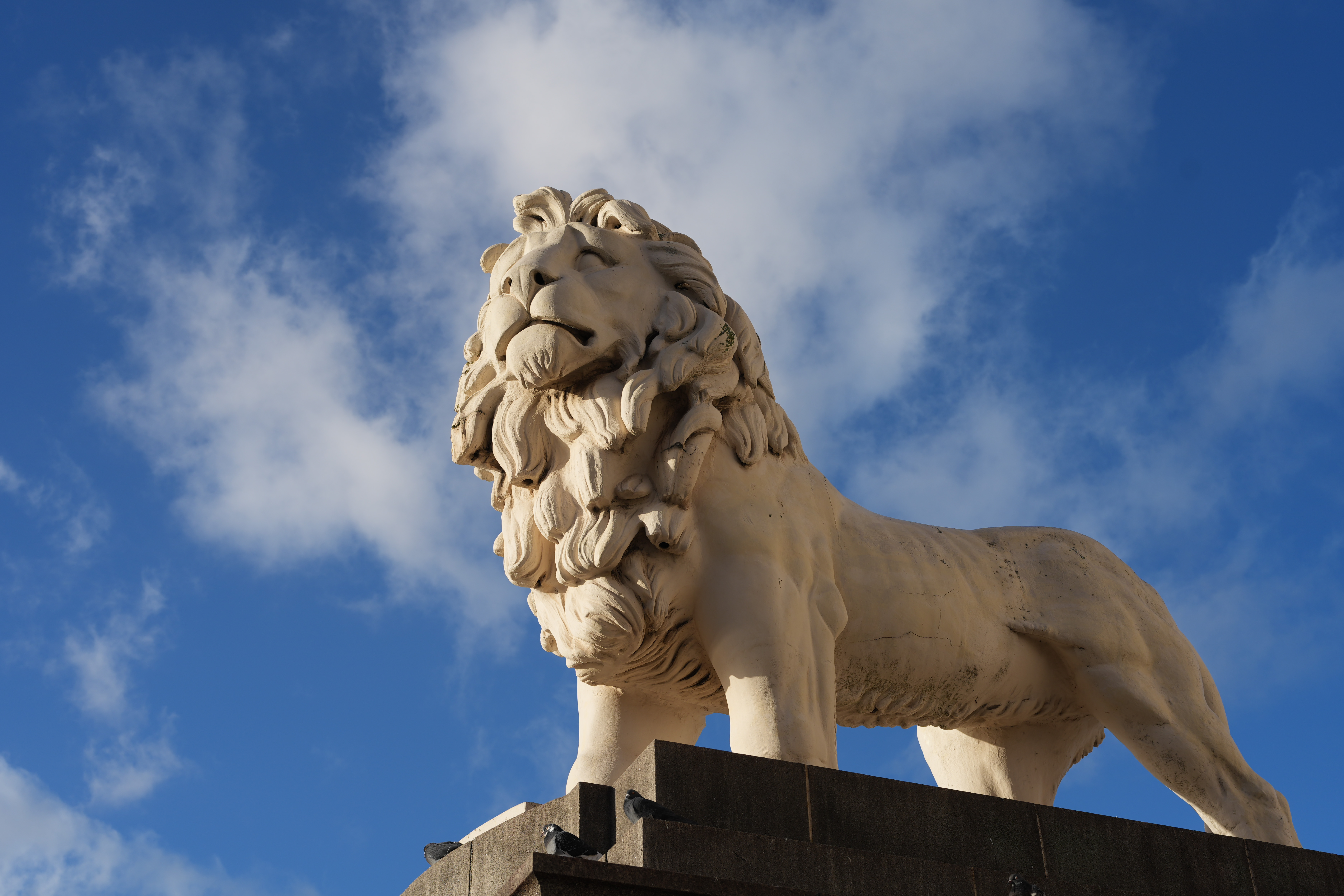 A statue of a lion set against a blue and cloudy sky
