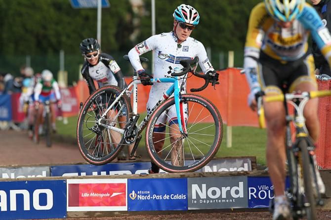 World Cup overall leader Katie Compton runs over a barrier toward victory at the Roubaix World Cup