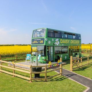 green bus with wooden fence and green lawn
