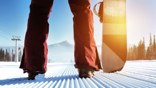 Snowboarder stands on slope backdrop