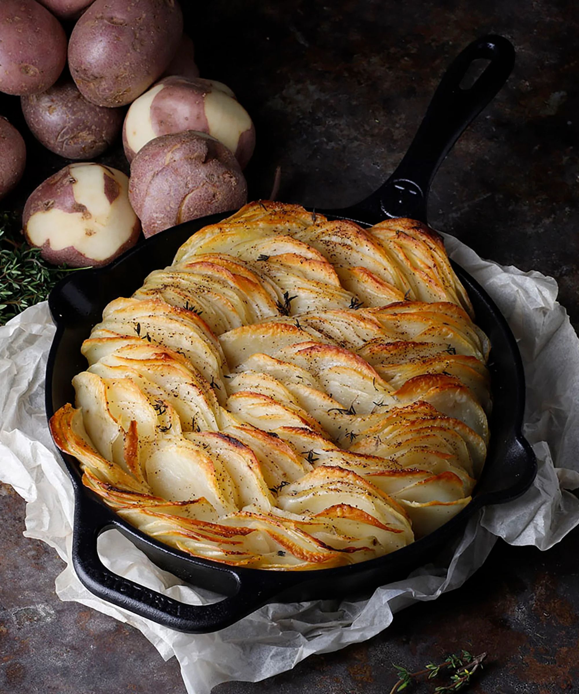 A black cast iron pan filled with finely sliced potatoes, fried and browned.