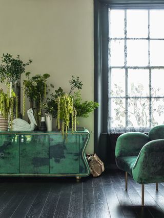 Green living room with black floorboards and green sideboard decorated with houseplants