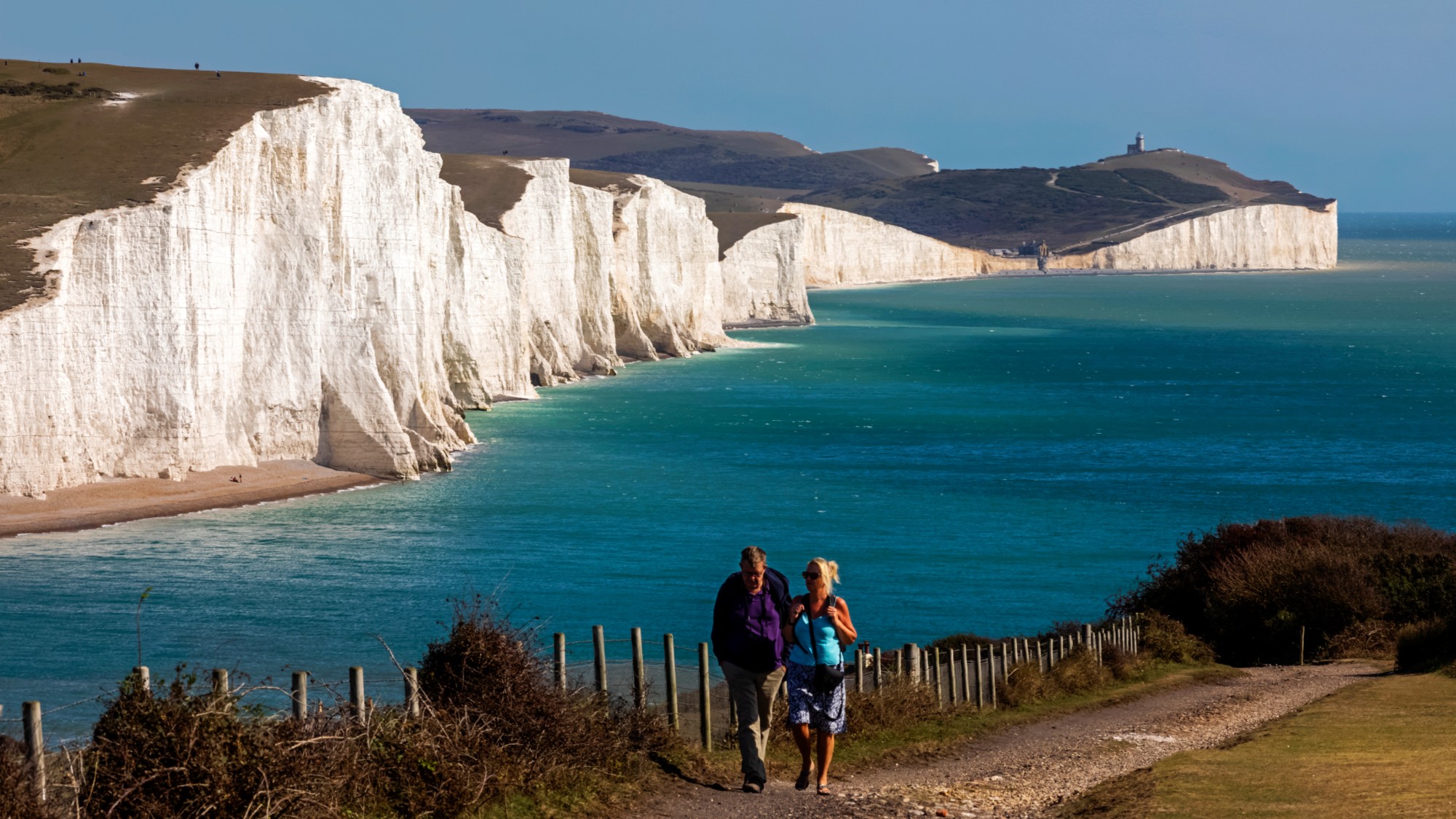 Walkers by white chalk Seven Sisters cliffs
