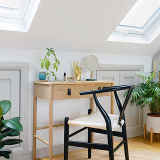 Room in the eaves with wooden desk between two skylights