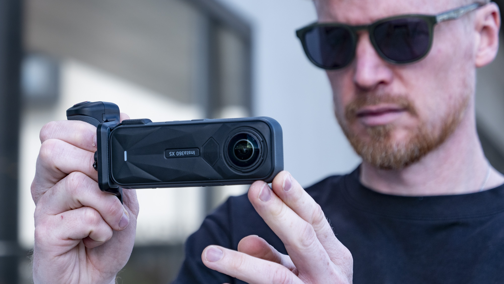 Insta360 X5 Photography Grip attached to the camera, in the hand
