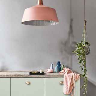 grey kitchen with pink hanging lights and plant pot