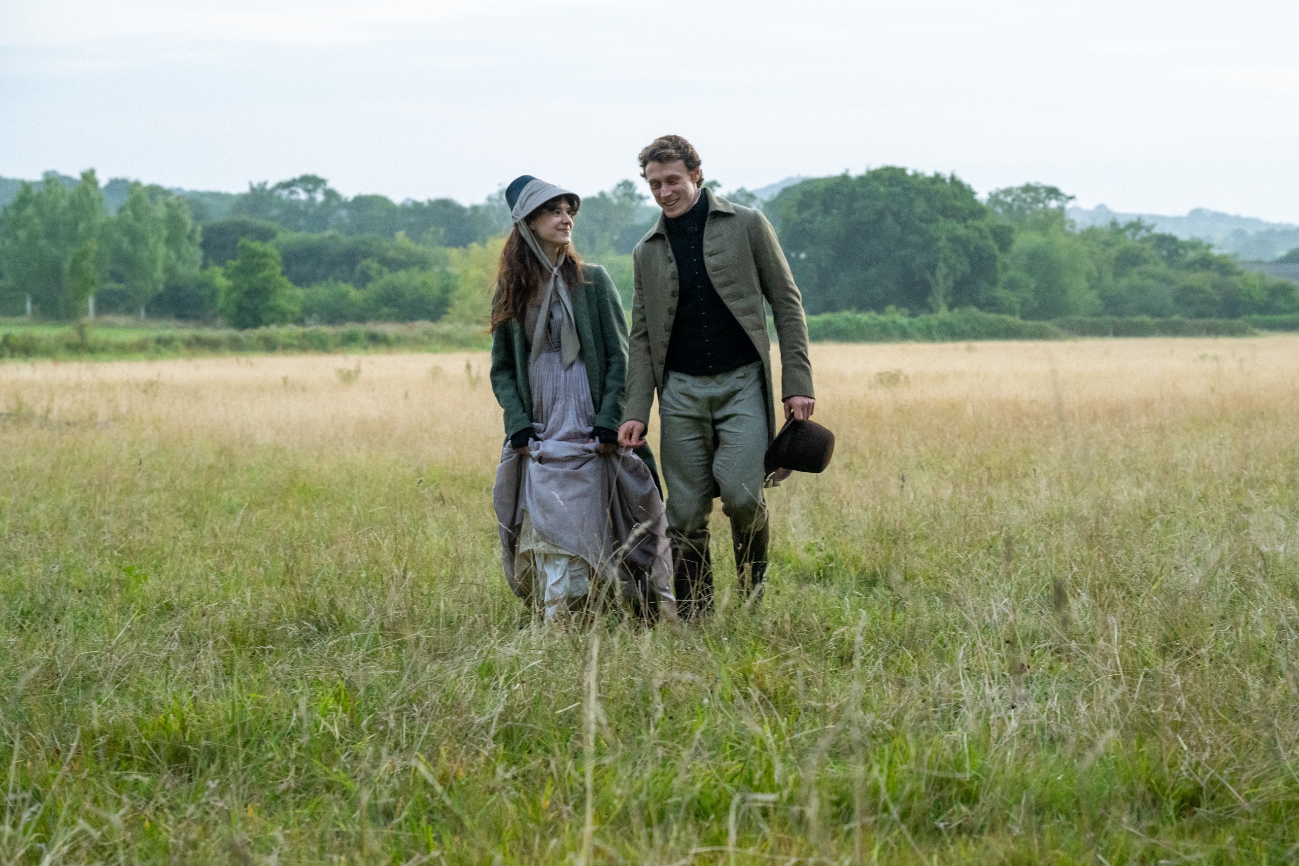 Daisy Edgar Jones and george mackay walk through a field as their respective characters in Sense and Sensibility