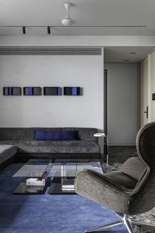 A living room with a dark gray sofa, and dark navy blue pillows