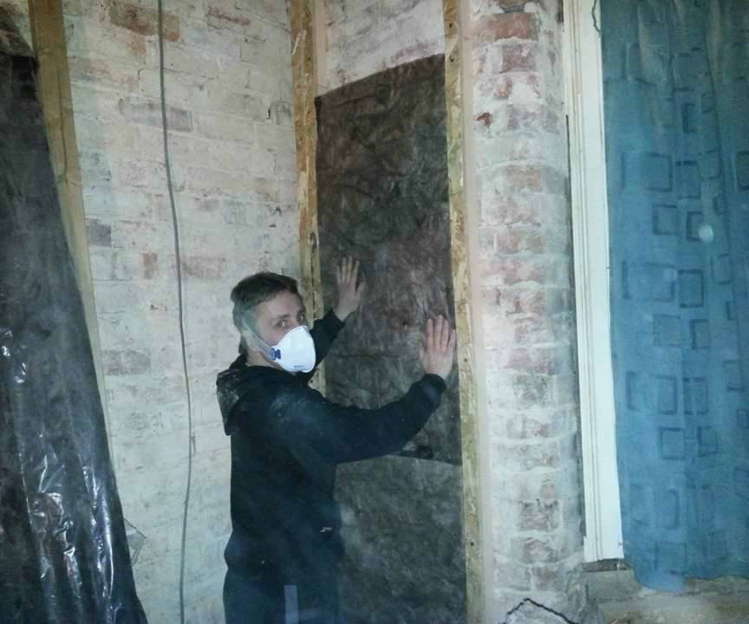 main installing internal wall insulation on walls of house