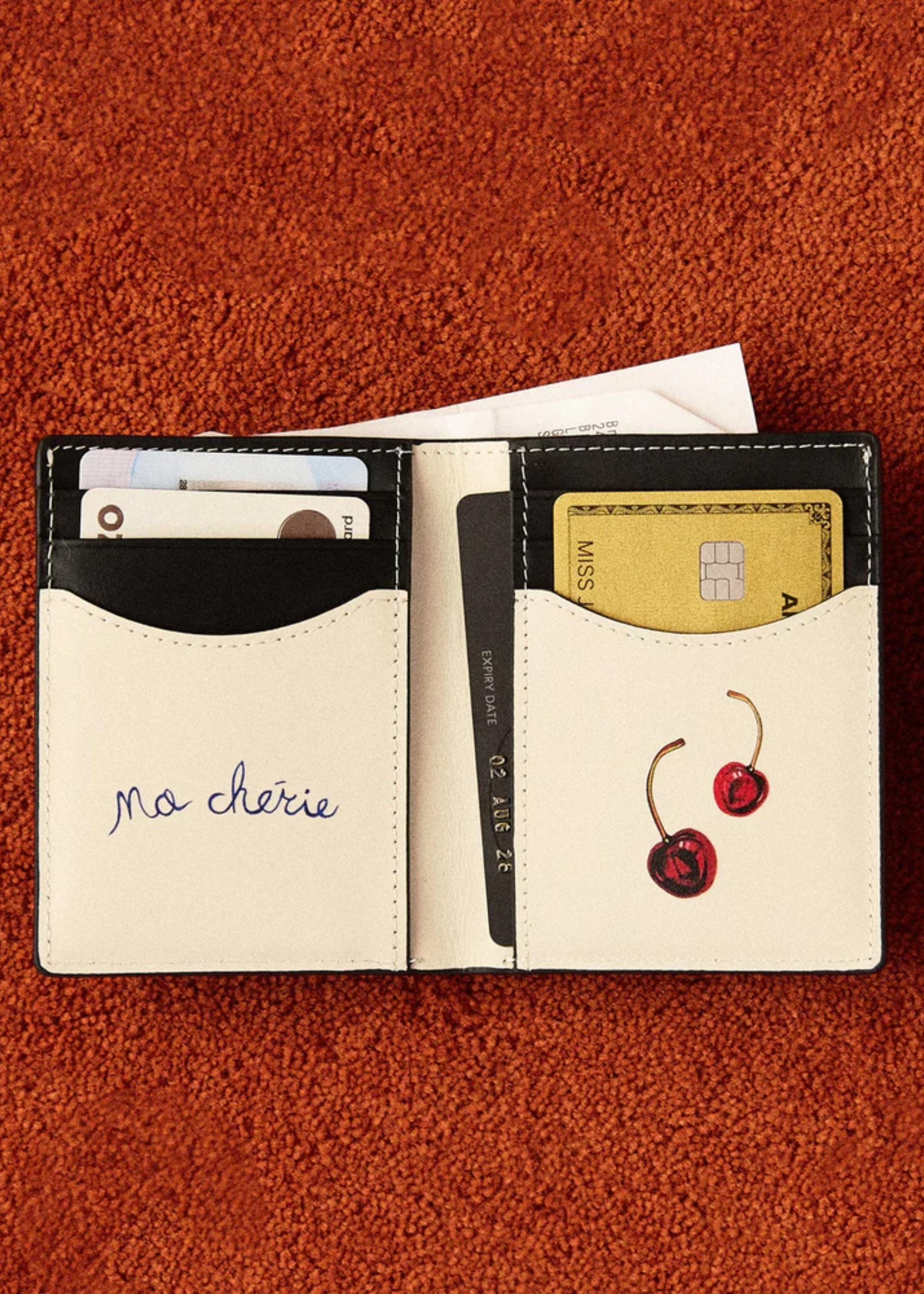 A wallet with cards inside placed on a red colored carpet