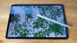 A photo of the Huawei Matepad 11 on a wooden table, an artwork is shown on the screen