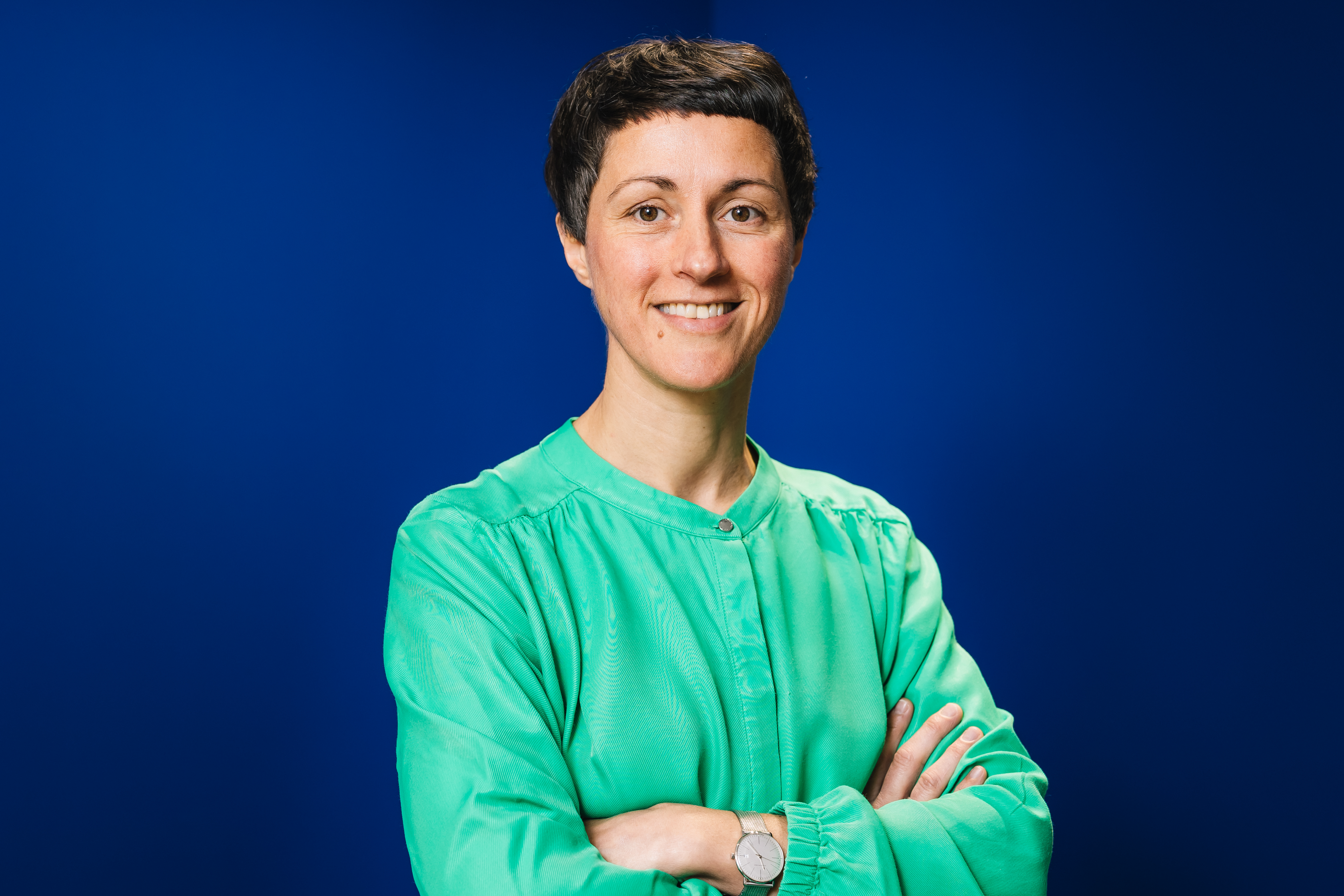 woman with short hair in green cardigan on blue background