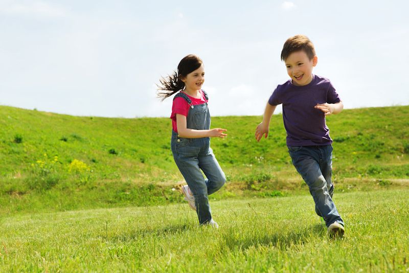 Children play tag in a green field