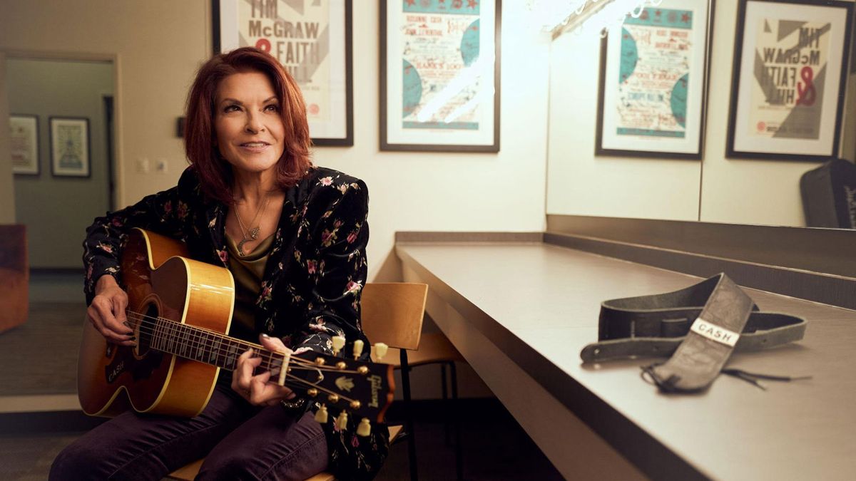 Rosanne Cash playing her Gibson acoustic guitar – her &#039;Cash&#039; strap lies beside her on a table