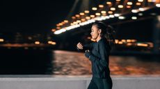 Woman checks her fitness tracker while running at night