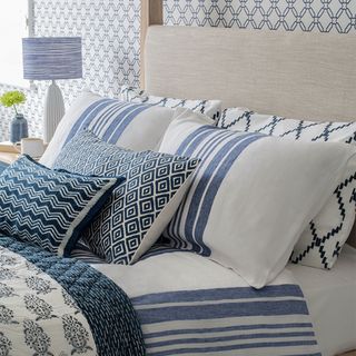 neutral bed with blue and white striped bedding and cushions