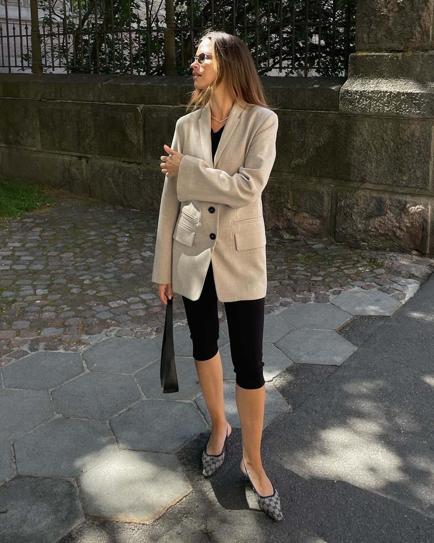 Finnish style influencer Johanna Piispa poses in a beige blazer, capri pants, a black shoulder bag, and printed slingback flats