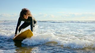 Woman about to stand up on a surfboard in the ocean