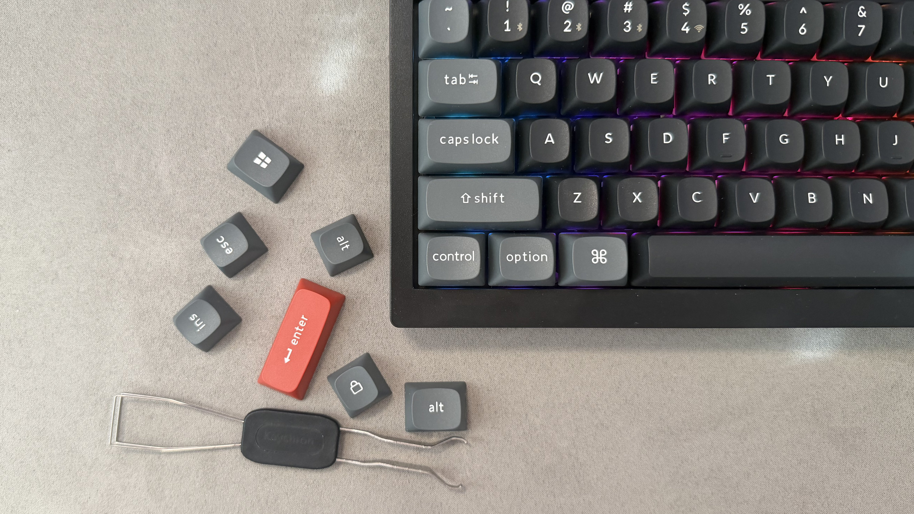 The Keychron V1 Ultra 8K, a key replacement tool and a selection of alternate key caps, including a red Enter key.