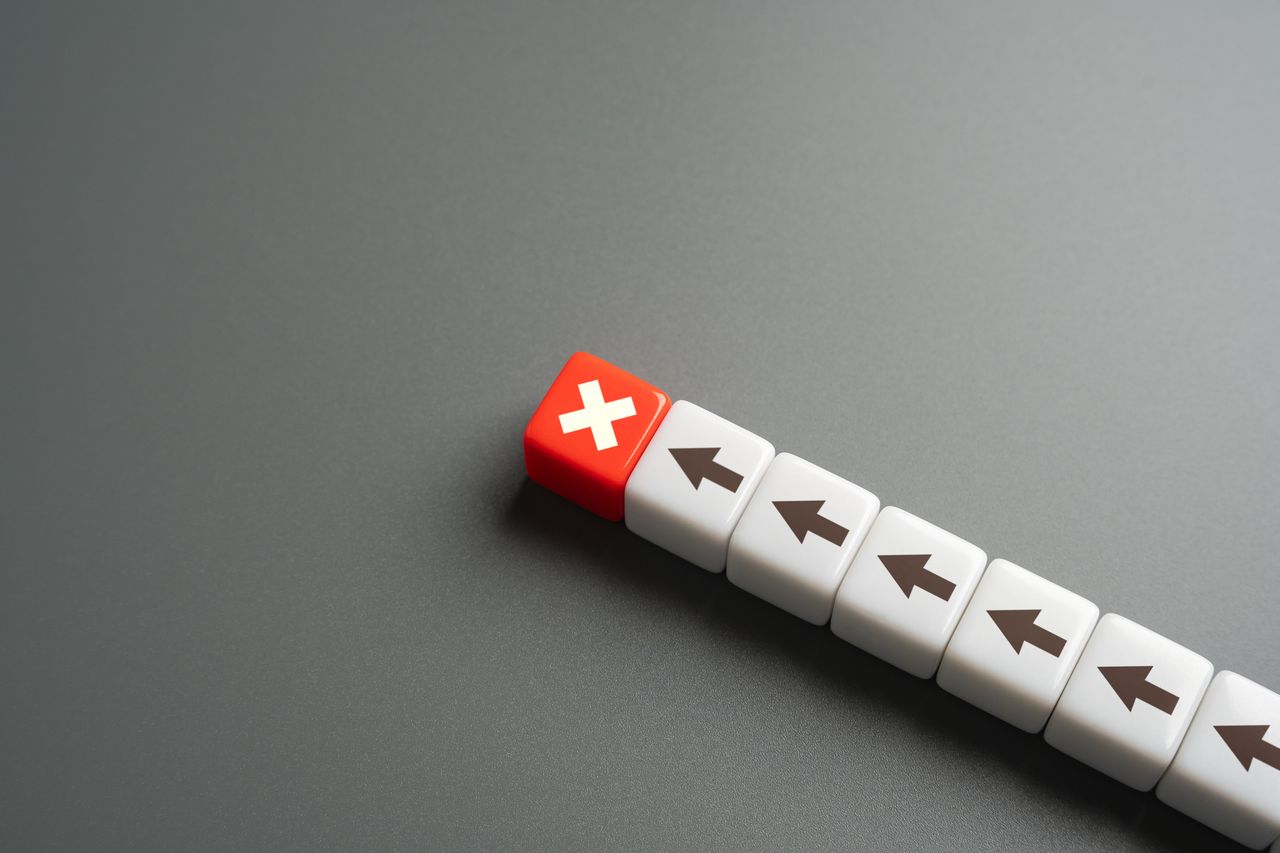 a line of white dice with black arrows on them and one red die with a white &quot;x&quot; at the top