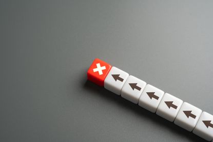 a line of white dice with black arrows on them and one red die with a white "x" at the top