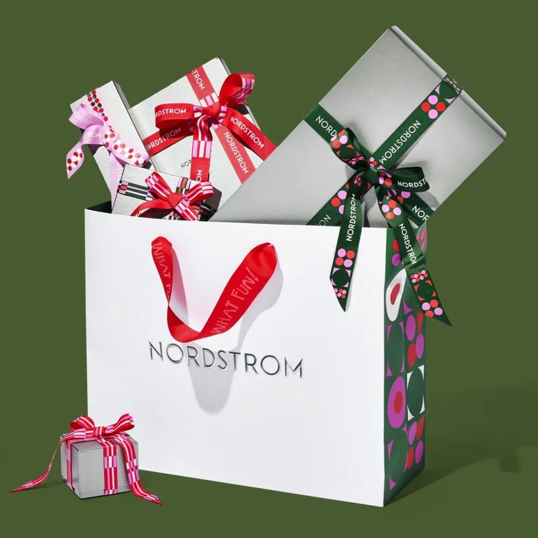 Nordstrom bag with wrapped gifts on green background 