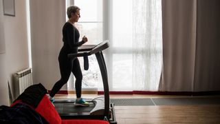 Woman running lightly on treadmill in living room, another great example of LISS cardio