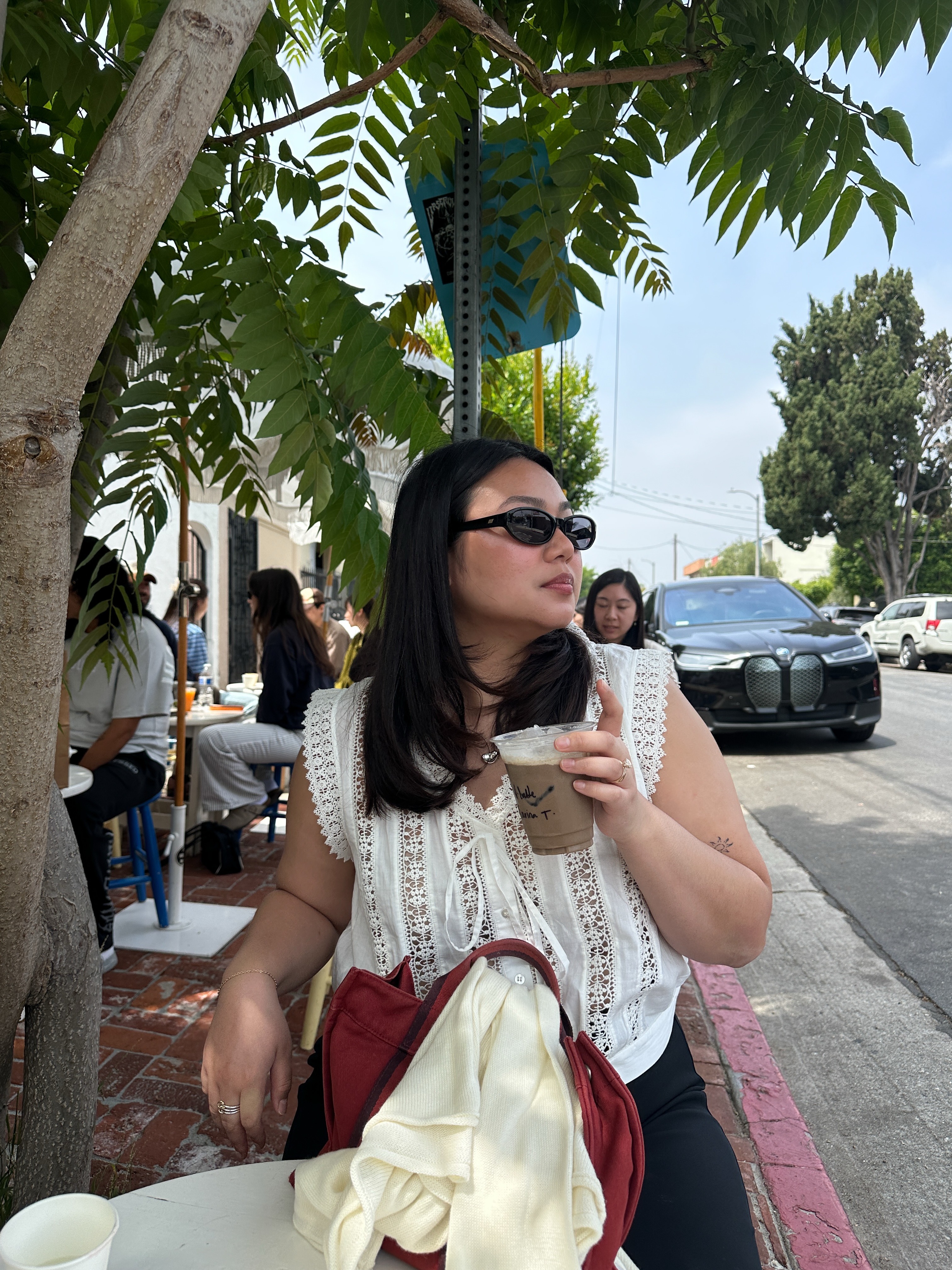 The woman is wearing an embroidered blouse, black pants, and a red handbag.