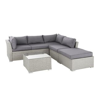 A rattan outdoor sofa with grey cushions
