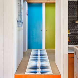 patterned blue and navy runner in a colourful hallway with two doors painted blue and green