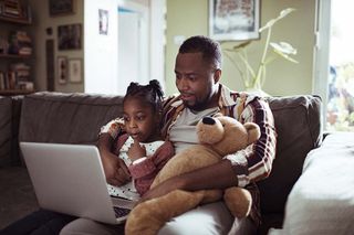 A father and daughter watching video on a laptop screen 