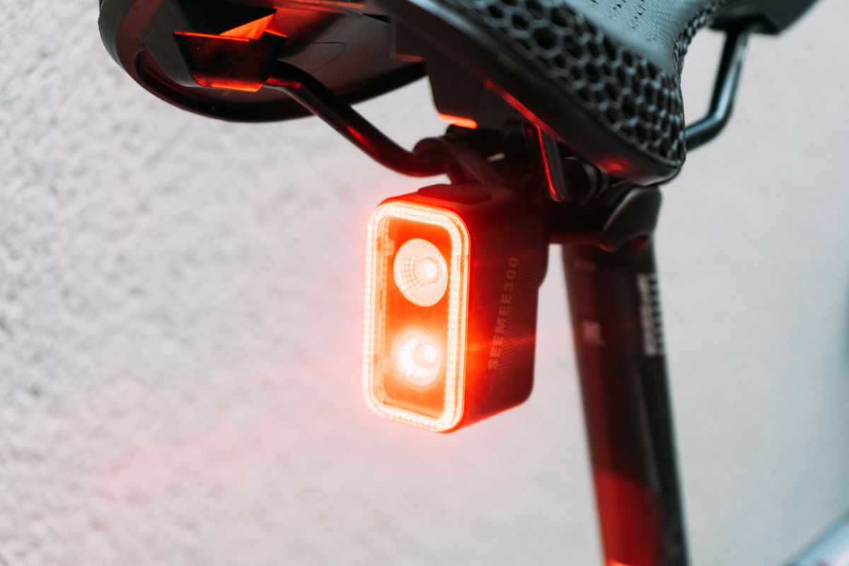 A large rectangular light mounted under the saddle rails of a bike saddle, switched on